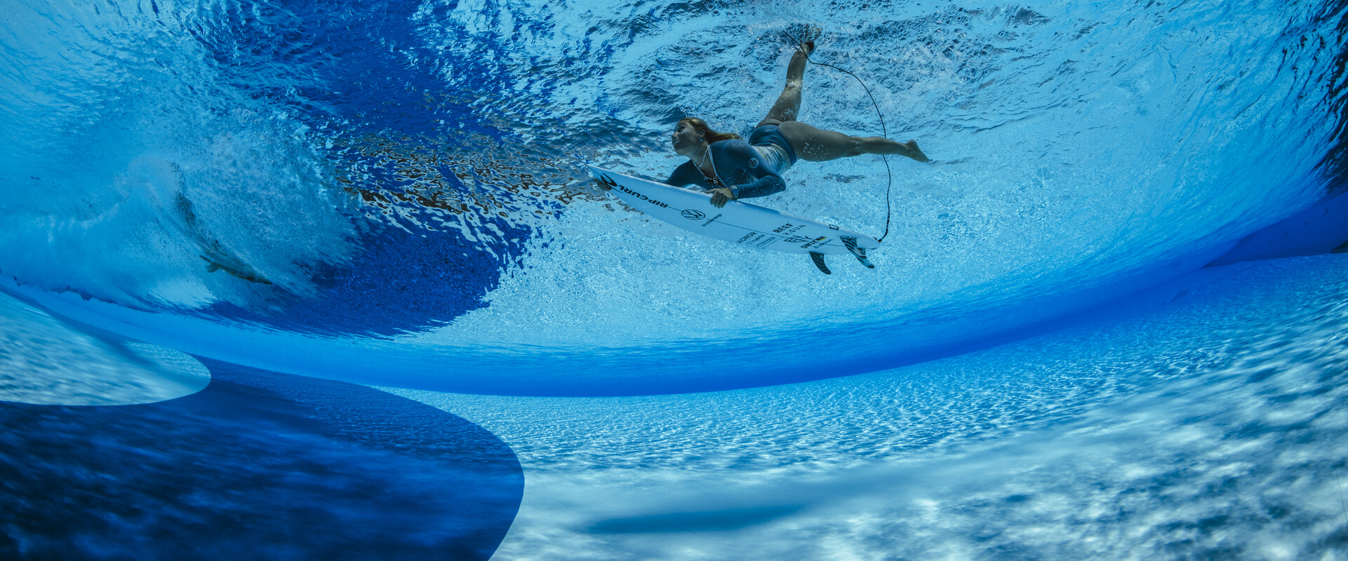 Im derzeit größten Wellenpark Europas kannst du das ganze Jahr über surfen. Das Bild zeigt eine Surferin beim Duckdive unter eine künstlichen Welle hindurch.
