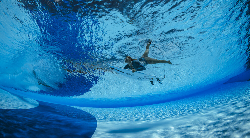 Im derzeit größten Wellenpark Europas kannst du das ganze Jahr über surfen. Das Bild zeigt eine Surferin beim Duckdive unter eine künstlichen Welle hindurch.